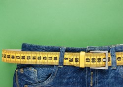 A pair of jeans with a tape measure around the waist