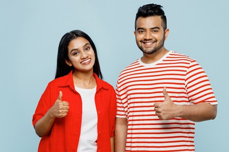 A man and woman looking happy with their thumbs up