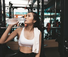 A girl drinking from a water bottle in a gym