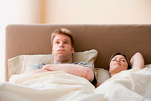 A frustrated young man in bed suffering from erectile dysfunction. Source medicalimages.com