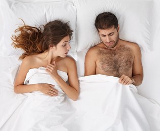An unhappy couple in bed suffering from erectile dysfunction