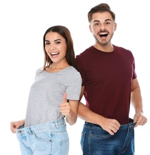 A happy couple showing their weight loss in over-sized jeans
